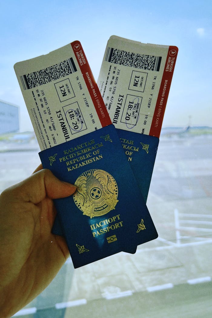 ours-journey A Kazakhstan passport holds two airline tickets against an airport backdrop in Warsaw, Poland.