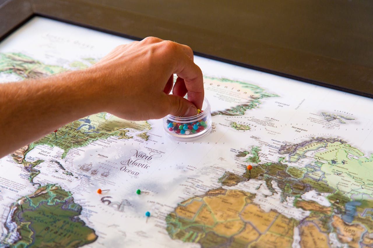 Crafting Captivating Headlines: Your awesome post title goes here A hand placing colorful pins on a world map, symbolizing travel planning and global exploration.